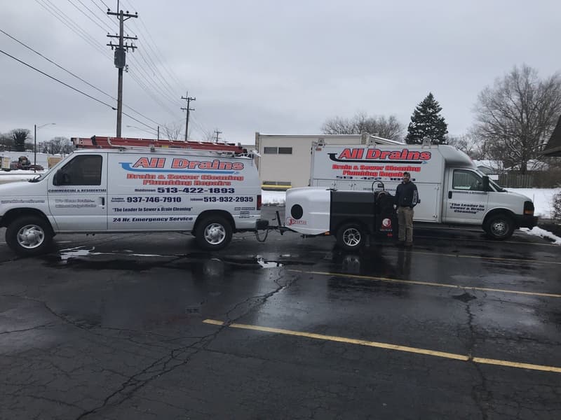 Two company service vans and a trailer jetter in a parking lot