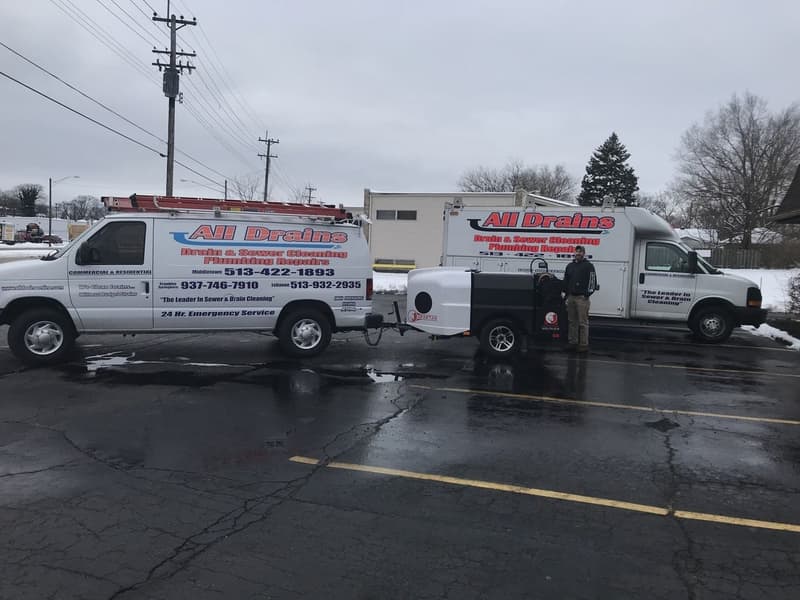 Two company service vans and a trailer jetter in a parking lot